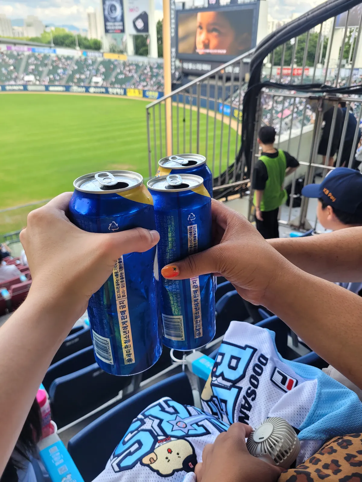Guests clinking beer cans over the outfield before a game at Jamsil Baseball Stadium