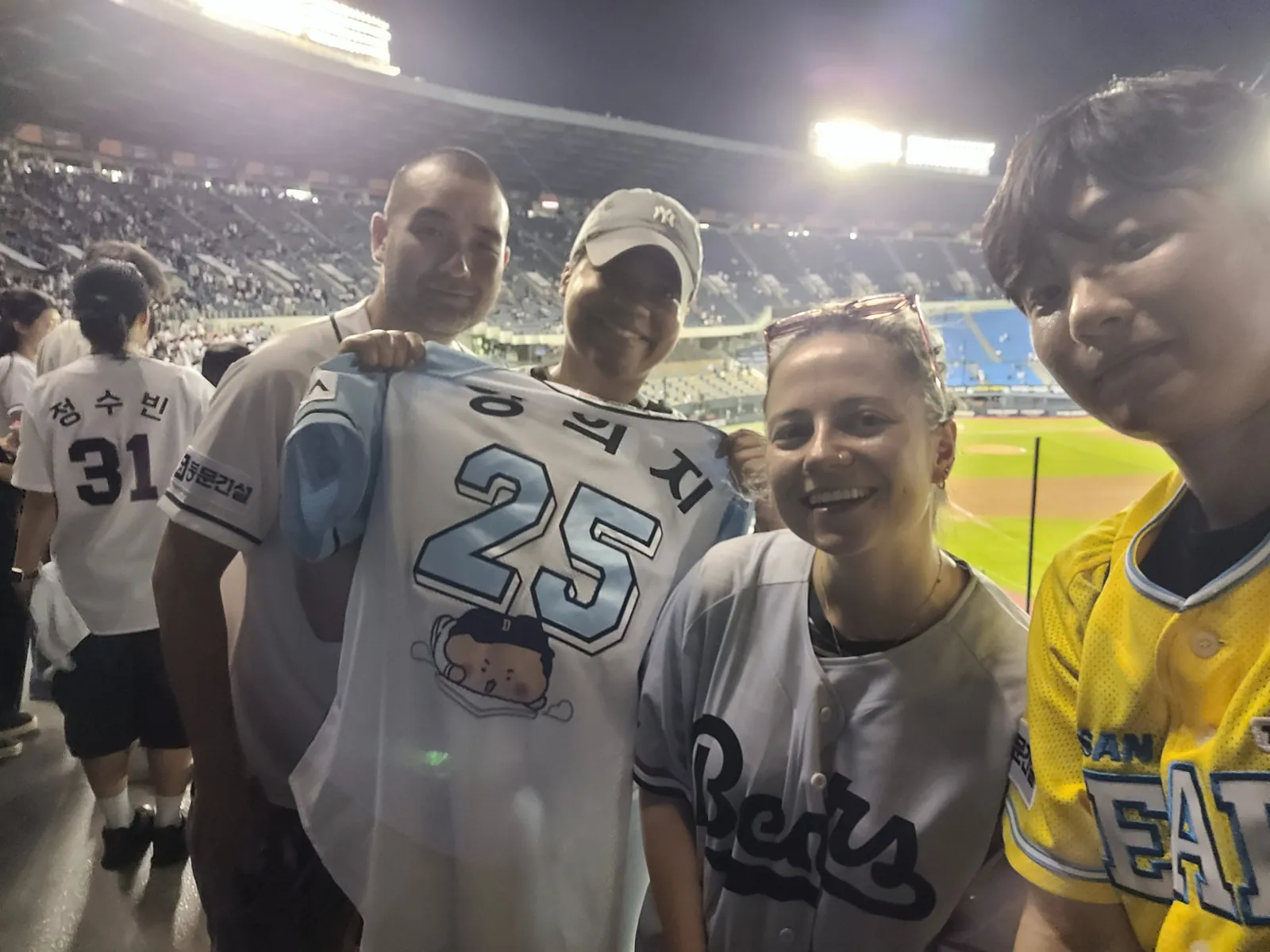 Guests and buddies holding a Doosan Bears jersey during a night game at Jamsil